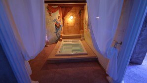 A room with a bathtub, a mural, and a sun-like decoration on the wall.