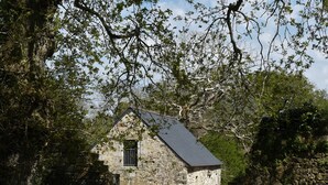 A stone building with a sloped roof, surrounded by trees. - Character cottage **** Manor of Kerdanet Poullan sur Mer Sud Finistère Brittany (Poullan-sur-Mer)