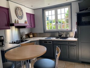 Uma cozinha com mesa de jantar, armários roxos, uma janela com vista e um forno embutido.