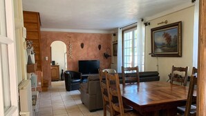 Un comedor con una mesa y sillas de madera, televisor y sofá.