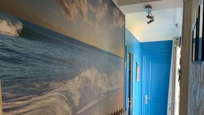Un pasillo con un mural de una ola, una puerta azul y una cerca de piquetes de madera.
