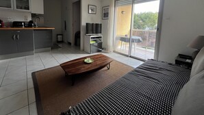 Een moderne woonkamer met een bank, een salontafel, een televisie en een schuifpui die naar een balkon leidt.