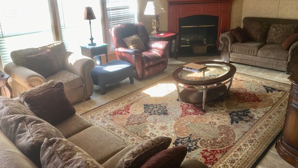 Un salon avec une cheminée, deux canapés, une table basse et un tapis à motifs.