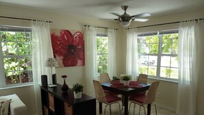 A dining area with a table and chairs, a ceiling fan, and large windows with curtains. - Sun, beach, and great savings –discover amazing discounts on dream destinations! (Cape Coral)