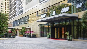 A modern hotel with a glass facade, outdoor seating area, and a red carpet entrance. - Shenzhen FY Hotel (Shenzhen)