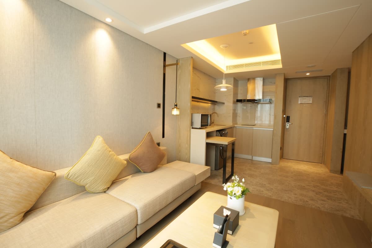 A modern living room with a sofa, a coffee table, and a kitchen area in the background.