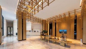 A modern hotel lobby with a marble floor, wooden reception desk, and a large TV screen. - Shenzhen FY Hotel (Shenzhen)