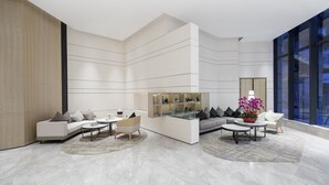 A modern interior with a sectional sofa, a coffee table, a side table, and a glass display unit. - Shenzhen FY Hotel (Shenzhen)