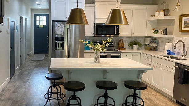 A modern kitchen with white cabinets, stainless steel appliances, and a central island with stools. - Pool Side Villa |Pet-Friendly Modern Escape w/ Games, Pool Toys, Bikes & More! Near St.George (Washington)