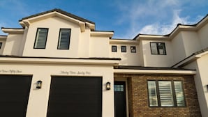 A two-story house with a garage, a brick section, and a well-maintained lawn. - Pool Side Villa |Pet-Friendly Modern Escape w/ Games, Pool Toys, Bikes & More! Near St.George (Washington)