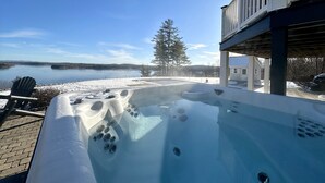 A hot tub with a view of a lake and a deck area.