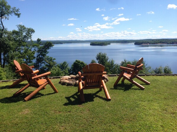 Two Adirondack chairs facing a lake with a clear sky. -  ADIRONDACK LUXURY LAKE ESTATE: POOL & HOT TUB! NEWLY RENOVATED! (Remsen)