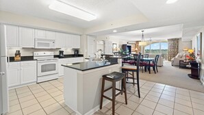 Een moderne keuken met witte kastjes, een centraal eiland en een eethoek met uitzicht.
