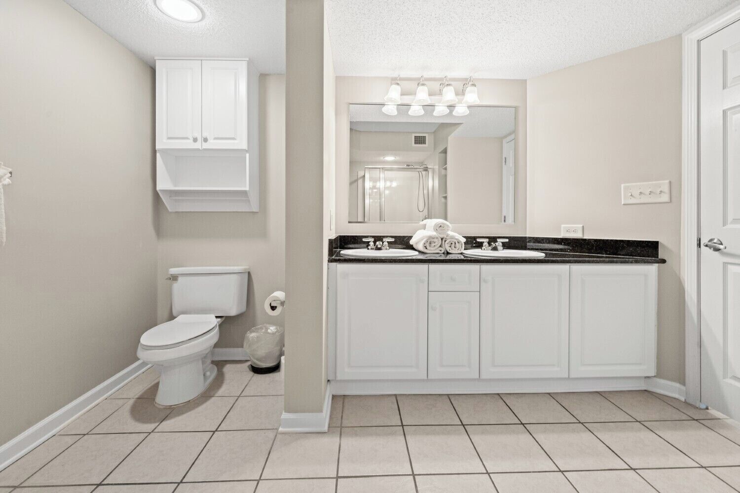 A bathroom with a toilet, sink, and mirror.