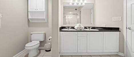 A bathroom with a toilet, sink, and mirror.