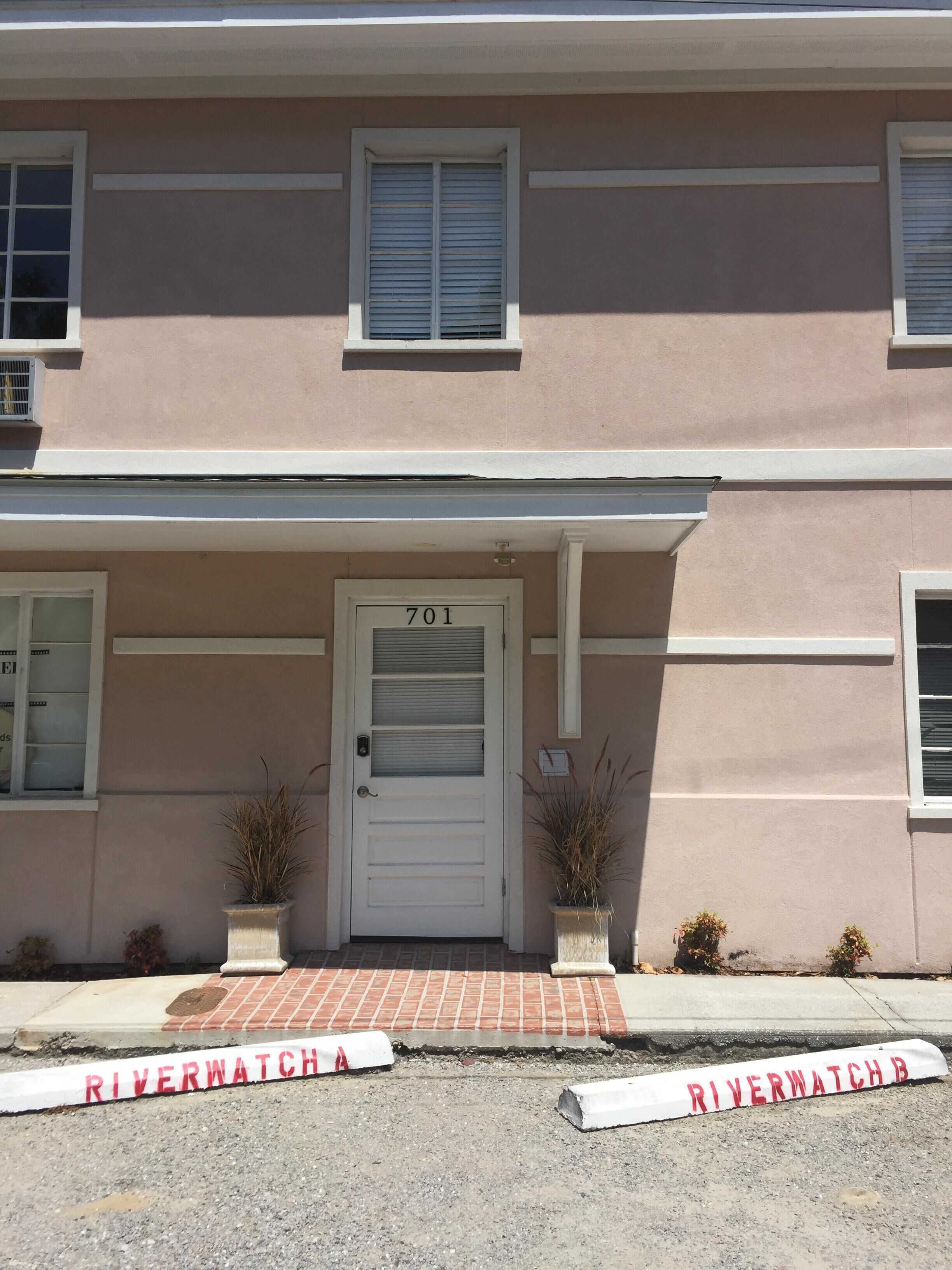 A two-story building with a white door marked '701' and a brick-paved entrance.
