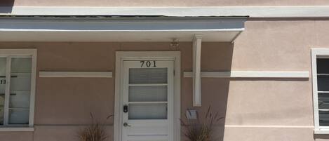 A two-story building with a white door marked '701' and a brick-paved entrance.