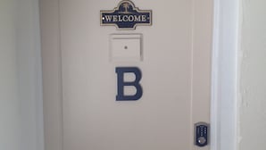 Una puerta con un letrero que dice 'WELCOME' encima y una 'B' grande en la puerta.