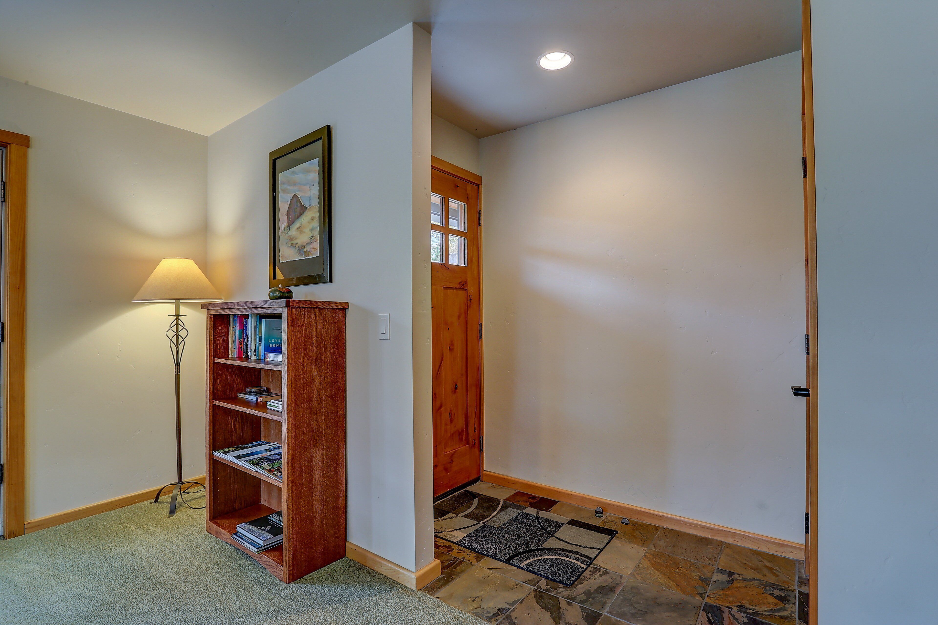 Un couloir avec une bibliothèque en bois, un lampadaire et une porte.