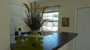 Une cuisine avec un plan de travail noir, une plante décorative dans un vase et un panneau portant l'inscription « ACHIEVE ».