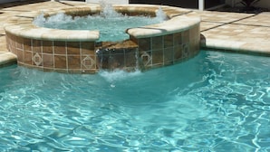 Une piscine dotée d’un espace avec jacuzzi, agrémenté de motifs en mosaïque et d’une fontaine.