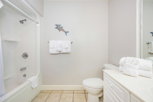 A bathroom with a bathtub, toilet, and a shower. There are towels on the wall and a towel rack.