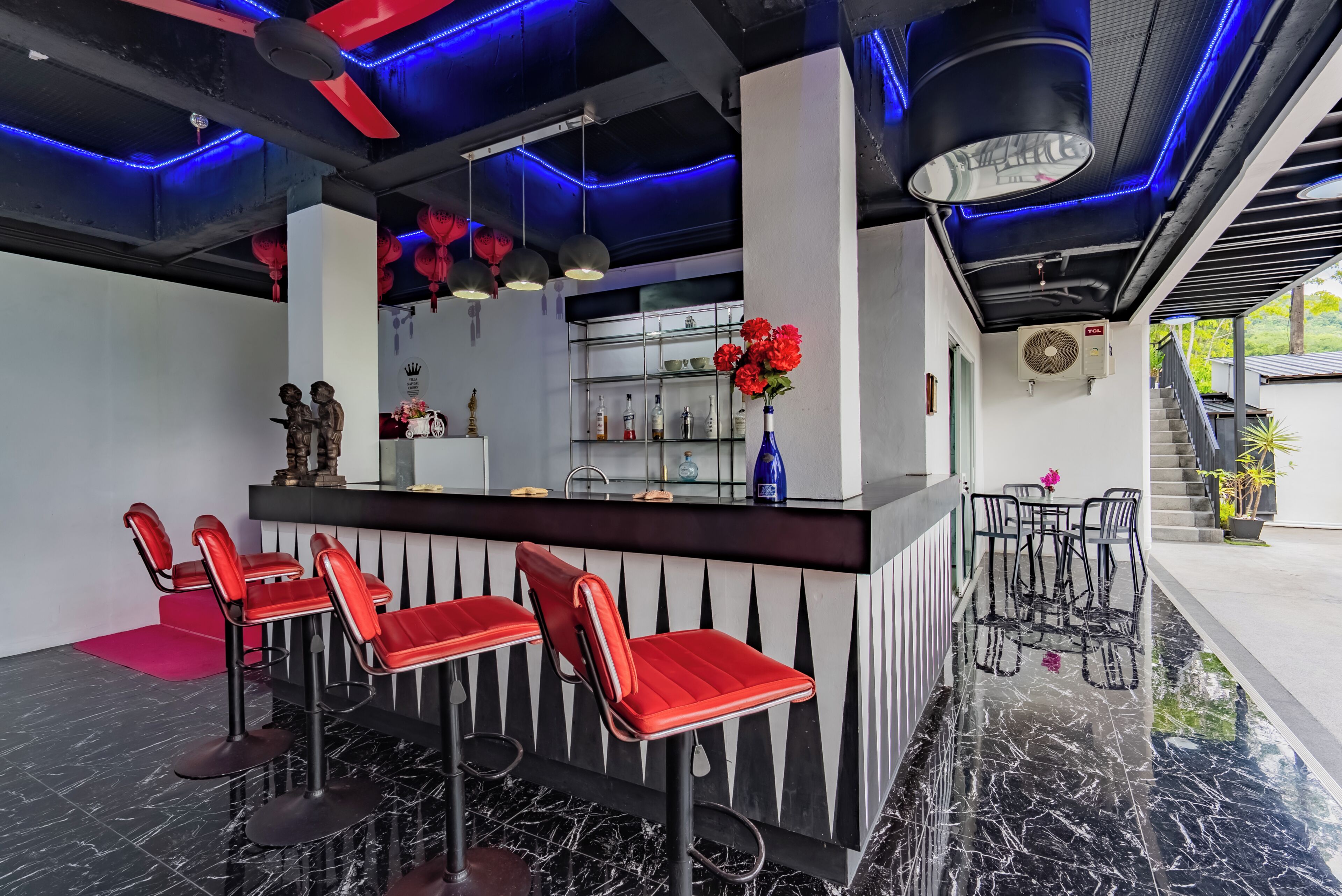 A bar area with a marble floor, red bar stools, a central bar counter, and a ceiling with blue LED lighting.