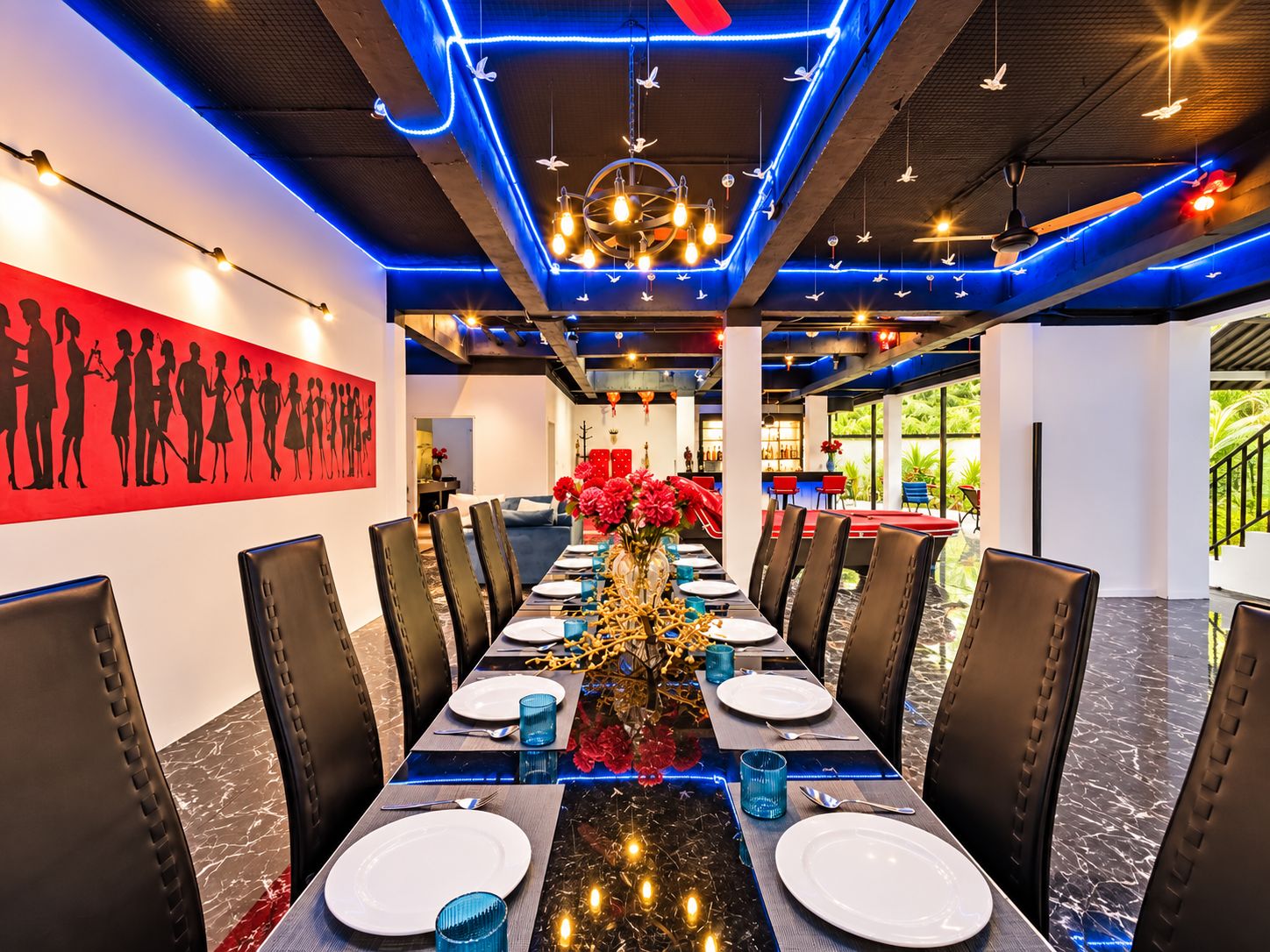 A dining area with a long table, chairs, and a central floral arrangement.