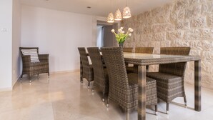 Un coin repas avec des meubles en osier, un mur en pierre et un vase rempli de fleurs.