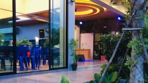 Un edificio moderno con amplios ventanales de vidrio, un interior luminoso y un área exterior ajardinada con plantas.