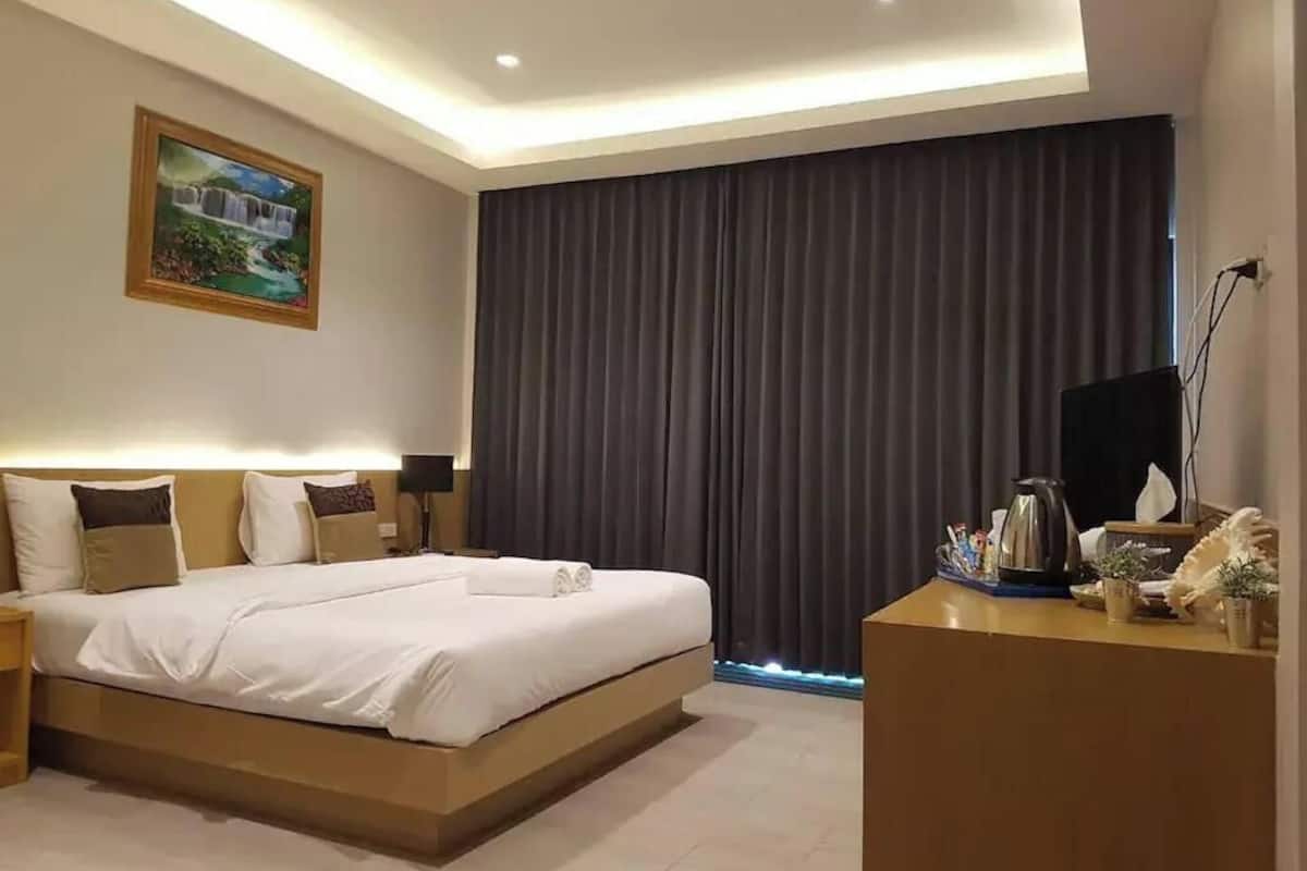 Une chambre d’hôtel moderne avec un grand lit, un bureau doté d’une bouilloire et un tableau au mur.