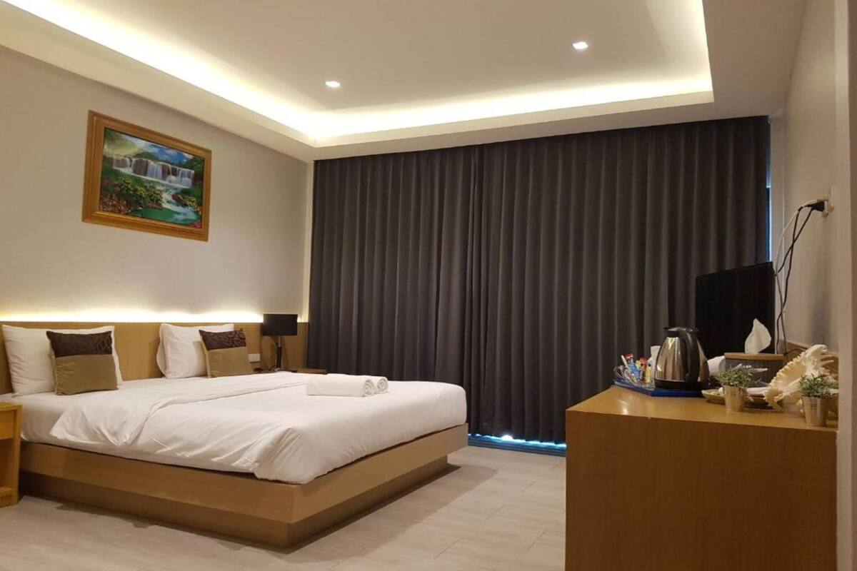Une chambre d’hôtel moderne avec un grand lit, un bureau doté d’une bouilloire et un tableau au mur.
