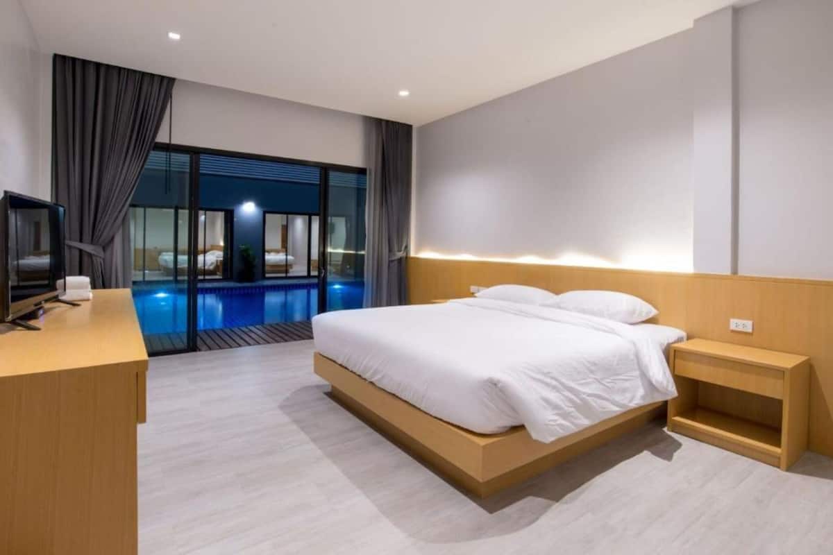 Une chambre d’hôtel moderne avec un grand lit, un bureau et une vue sur une piscine intérieure.