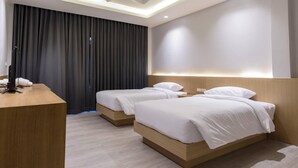 Habitación de hotel con dos camas, un escritorio y un diseño moderno en el techo.