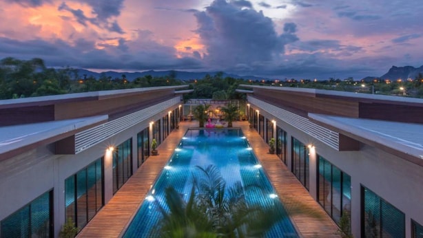 Un hotel moderno con una piscina central, rodeado de paredes de vidrio y senderos de madera.
