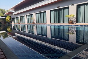 A modern building with a swimming pool, large windows, and potted plants. - Mayor Hotels&Villa Cha-Am (Cha-am)
