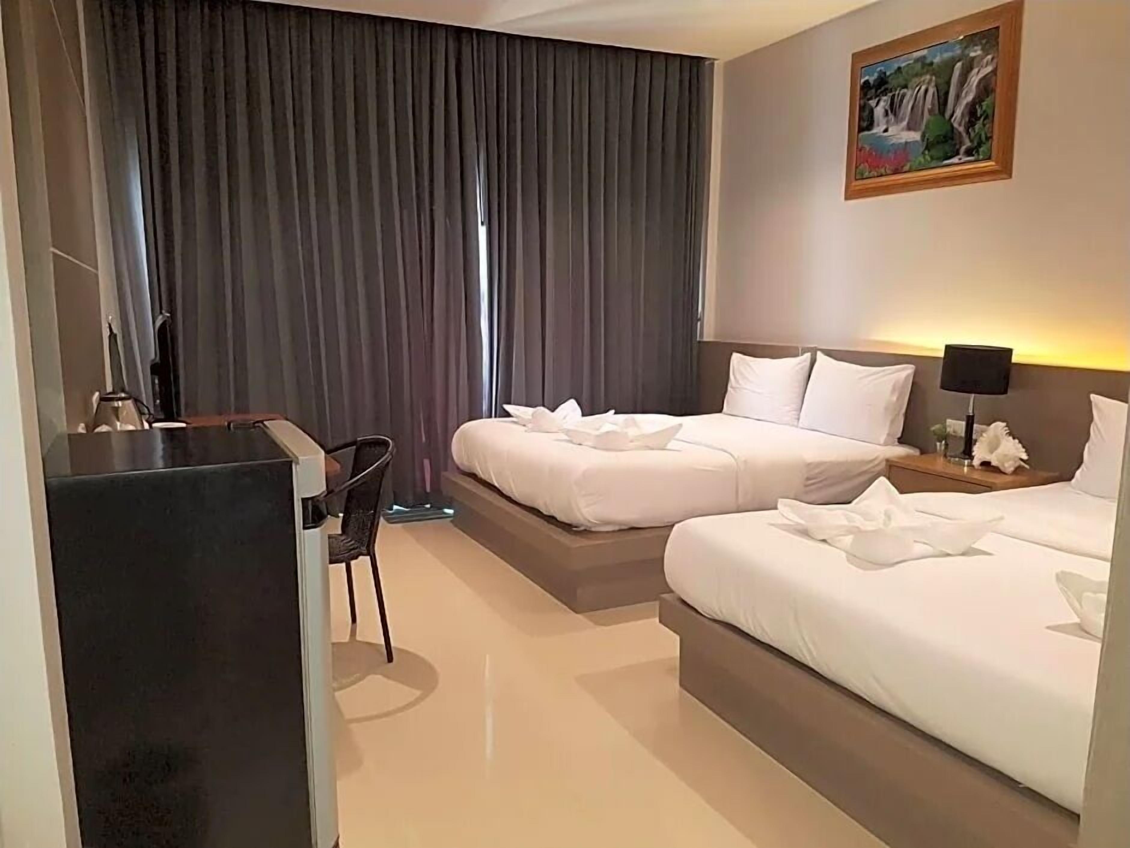 Une chambre d’hôtel avec deux lits, un bureau et une chaise.