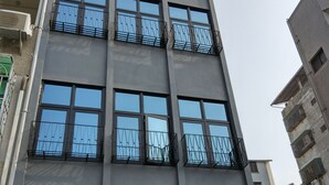 A multi-story building with balconies and large windows. - OYAJI Guesthouse (Tainan)