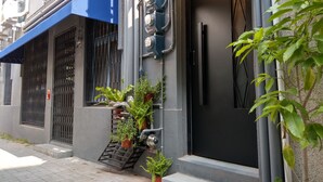 A residential building with a blue awning, a black door, and potted plants on the steps. - OYAJI Guesthouse (Tainan)