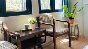 A room with a wooden dining table, two chairs, a potted plant, and a small side table. - OYAJI Guesthouse (Tainan)