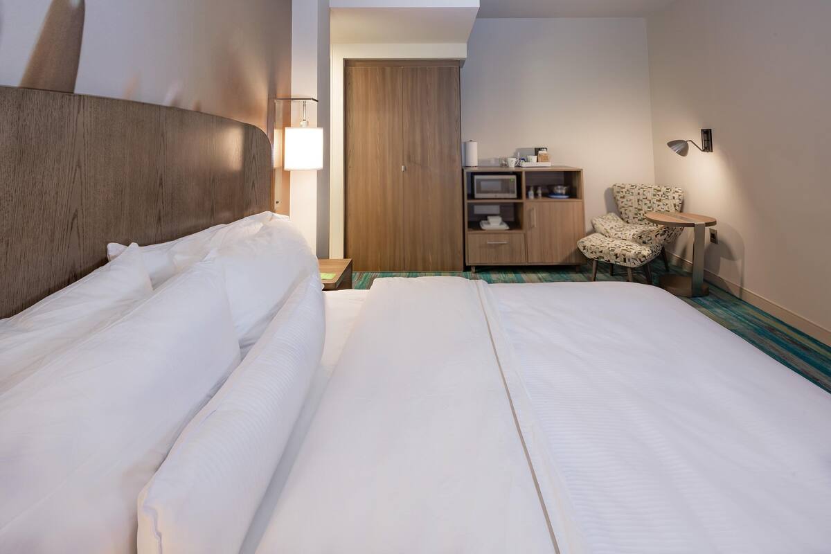 Hotellihuone, jossa on suuri sänky, puinen vaatekaappi, pieni työpöytä tuolilla ja televisio.