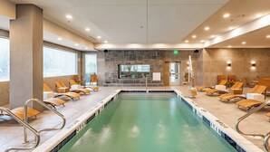 A large indoor swimming pool with multiple lanes, surrounded by lounge chairs and a stone wall. - Element by Marriott Dallas Downtown East (Dallas)