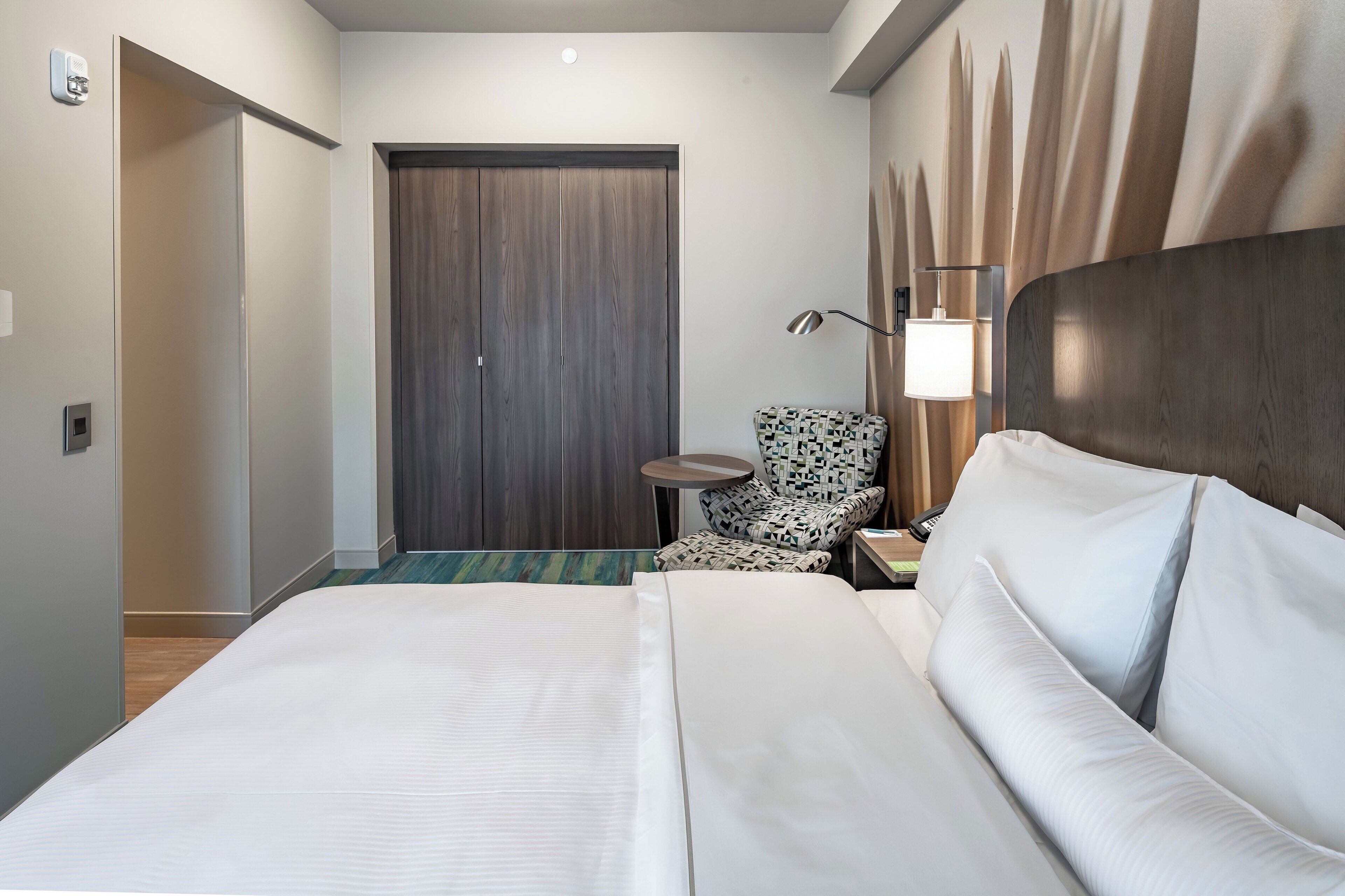 Una habitación de hotel con una cama grande, una silla, un escritorio y una puerta.