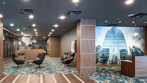 A modern lobby with a reception desk, two seating areas, and a large mural of a building. - Element by Marriott Dallas Downtown East (Dallas)