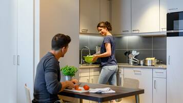 Una cocina moderna con una mesa de comedor y sillas, un lavamanos y una estufa.