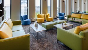 Un espacio lounge moderno con diversas opciones de asientos, ventanas amplias y vista a la ciudad.