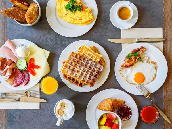 A breakfast spread with various dishes including eggs, waffles, and pastries.
