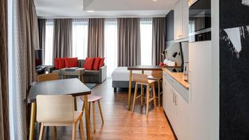 Una habitación de hotel moderna con comedor, sofá, cama y kitchenette.
