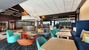 A modern lounge area with seating arrangements, a kitchen area, and a view of the outdoors.