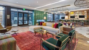 Un moderno vestíbulo de hotel con sofá, sillas, una mesa de centro y una zona de bar.